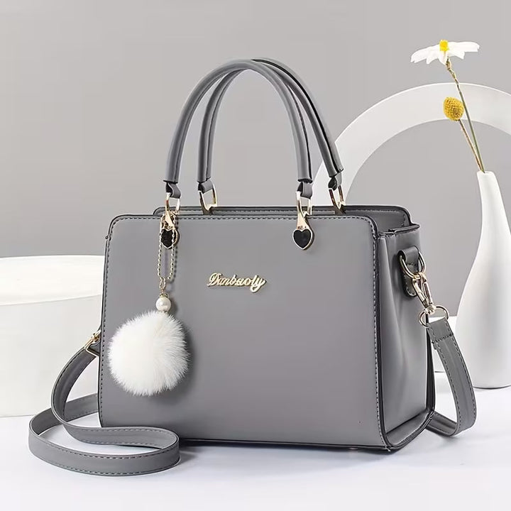 Sanika – Handtasche Mit Pompon Anhänger Und Schulterriemen